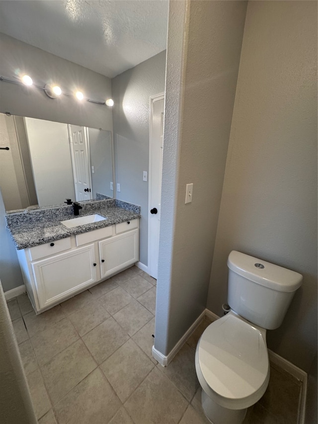 bathroom featuring vanity, a textured ceiling, toilet, and tile patterned floors