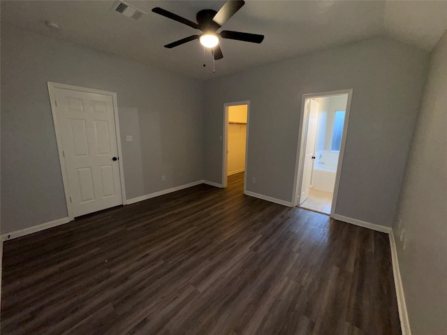 unfurnished bedroom featuring lofted ceiling, ceiling fan, connected bathroom, dark wood-type flooring, and a closet