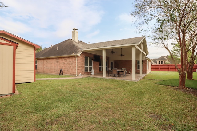 rear view of property featuring ceiling fan, a yard, and a patio area