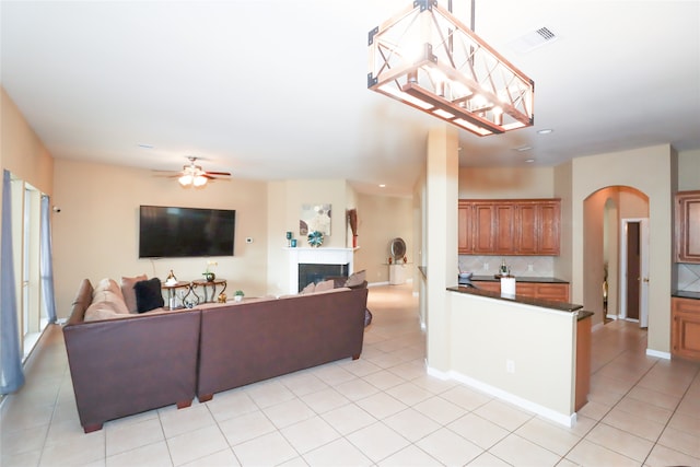 tiled living room with ceiling fan with notable chandelier