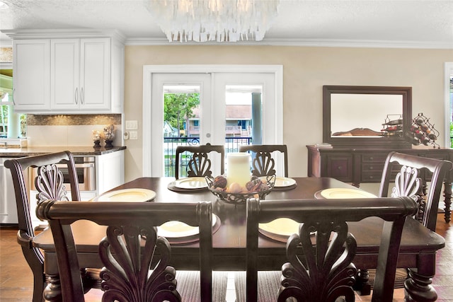 dining space featuring french doors, a wealth of natural light, ornamental molding, and a notable chandelier