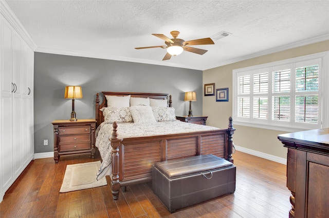 bedroom featuring a textured ceiling, ceiling fan, crown molding, and dark wood-type flooring