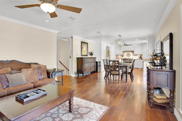 living room with a textured ceiling, hardwood / wood-style flooring, and crown molding