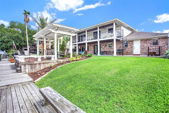 back of house with a pergola, ceiling fan, a balcony, and a lawn