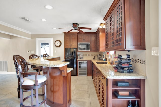 kitchen with black fridge, beverage cooler, crown molding, sink, and stainless steel microwave