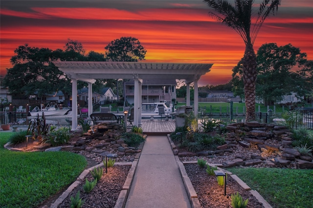 back house at dusk with a pergola and a wooden deck