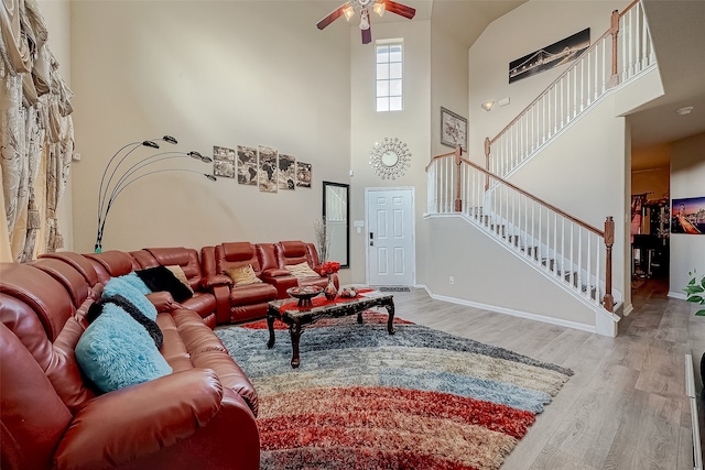 living room with a high ceiling, hardwood / wood-style flooring, and ceiling fan