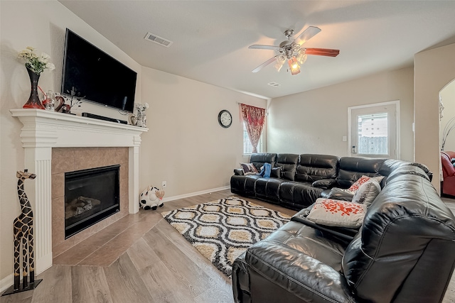 living room featuring a fireplace, light hardwood / wood-style floors, and ceiling fan