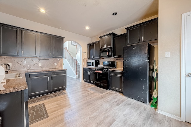 kitchen with light hardwood / wood-style floors, black appliances, sink, and backsplash