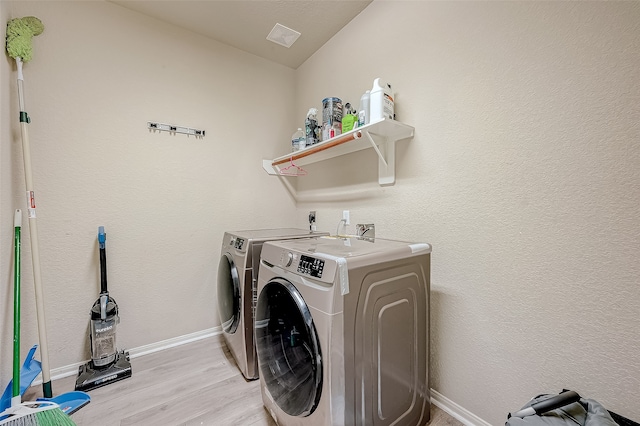 washroom with separate washer and dryer and light hardwood / wood-style flooring