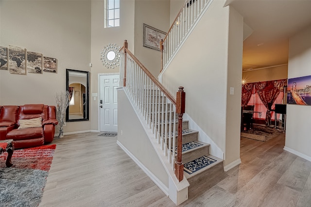 stairway with hardwood / wood-style flooring and a towering ceiling