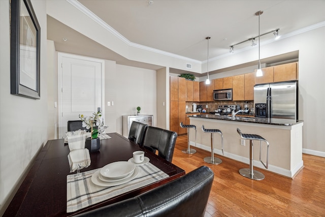 dining room featuring ornamental molding, light hardwood / wood-style flooring, and rail lighting