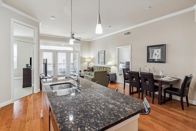 kitchen with a center island with sink, hardwood / wood-style flooring, sink, and decorative light fixtures