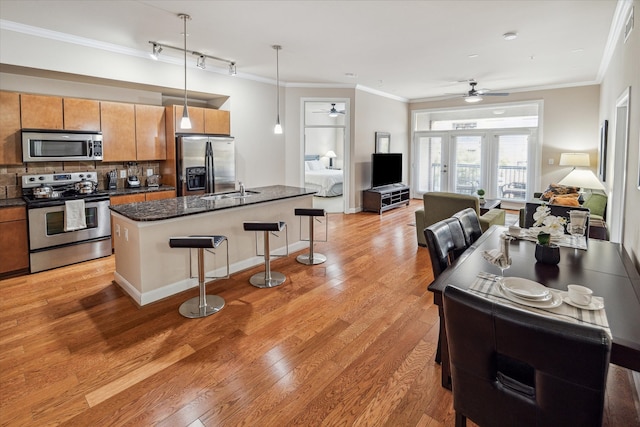 kitchen featuring hanging light fixtures, ceiling fan, a breakfast bar area, light hardwood / wood-style flooring, and stainless steel appliances