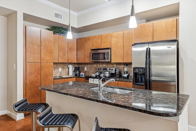 kitchen featuring a kitchen breakfast bar, hardwood / wood-style flooring, sink, pendant lighting, and stainless steel appliances