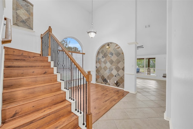 stairway with high vaulted ceiling and tile patterned flooring