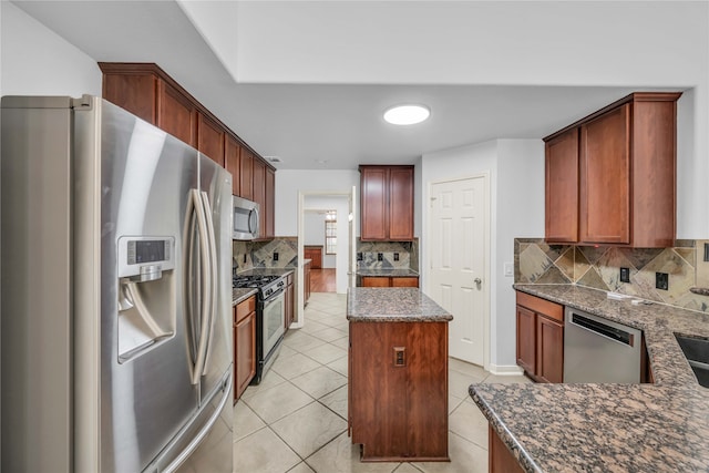 kitchen featuring appliances with stainless steel finishes, decorative backsplash, dark stone countertops, and light tile patterned floors