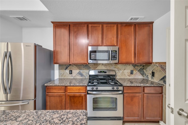 kitchen featuring stainless steel appliances, stone counters, and backsplash