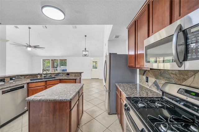 kitchen featuring sink, a textured ceiling, stainless steel appliances, and a kitchen island