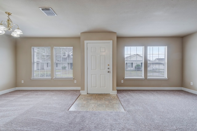 carpeted foyer with an inviting chandelier and a textured ceiling