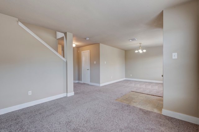 spare room with a chandelier and light carpet