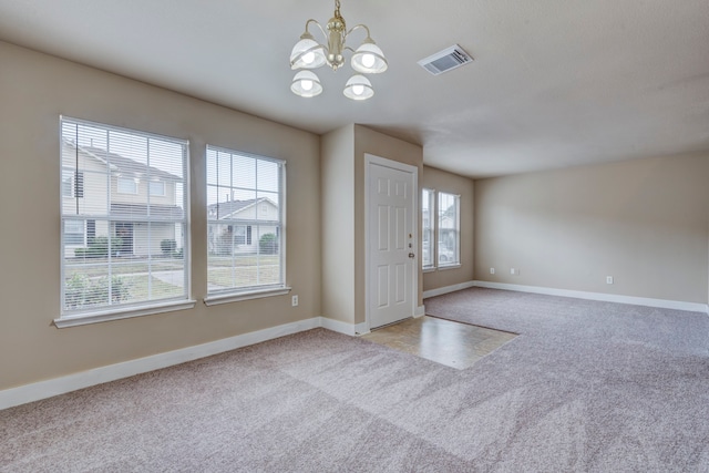 carpeted entrance foyer featuring a notable chandelier