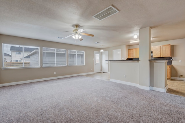 unfurnished living room featuring light carpet, a textured ceiling, and ceiling fan