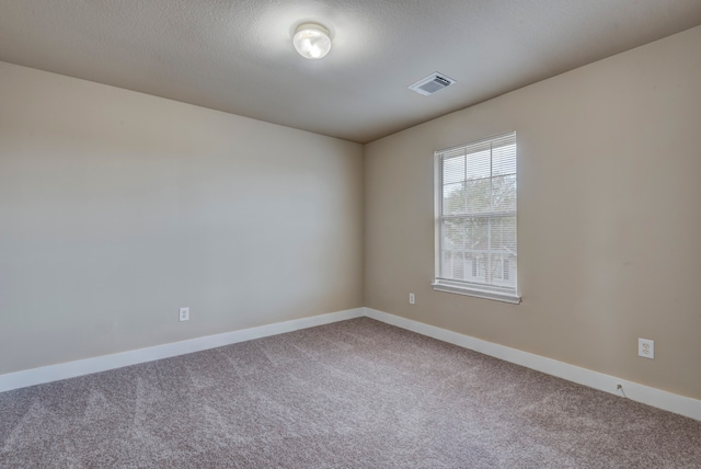 unfurnished room with a textured ceiling and carpet flooring