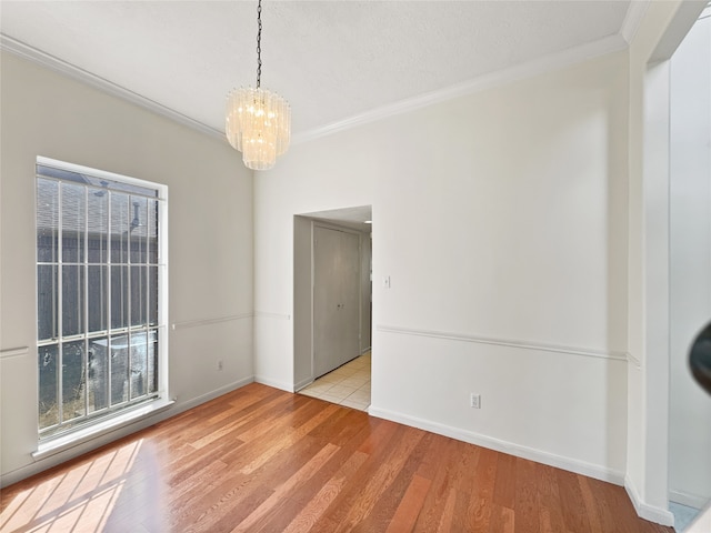 interior space featuring ornamental molding, a notable chandelier, a textured ceiling, and light hardwood / wood-style floors