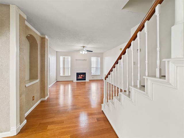 unfurnished living room featuring a textured ceiling, light wood-type flooring, and ceiling fan