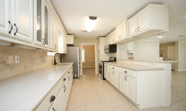 kitchen featuring stainless steel appliances, sink, tasteful backsplash, light tile patterned floors, and white cabinets