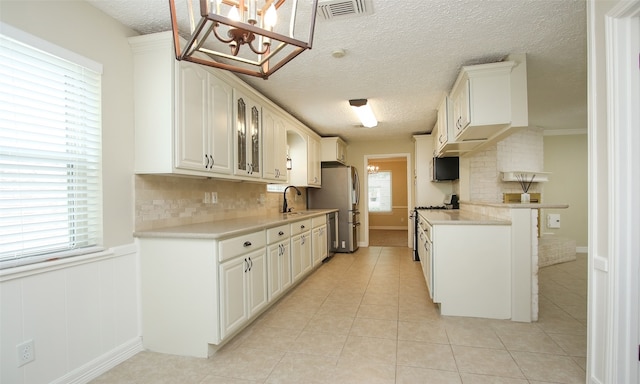 kitchen featuring white gas stove, a wealth of natural light, white cabinets, and backsplash