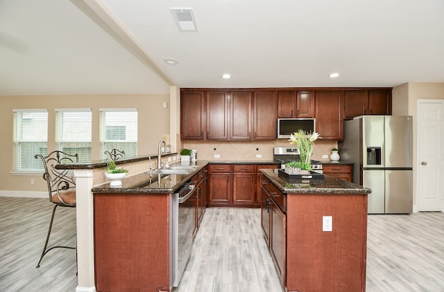 kitchen featuring light hardwood / wood-style flooring, kitchen peninsula, stainless steel appliances, backsplash, and sink