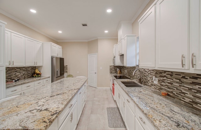 kitchen featuring sink, white cabinets, light stone counters, and tasteful backsplash