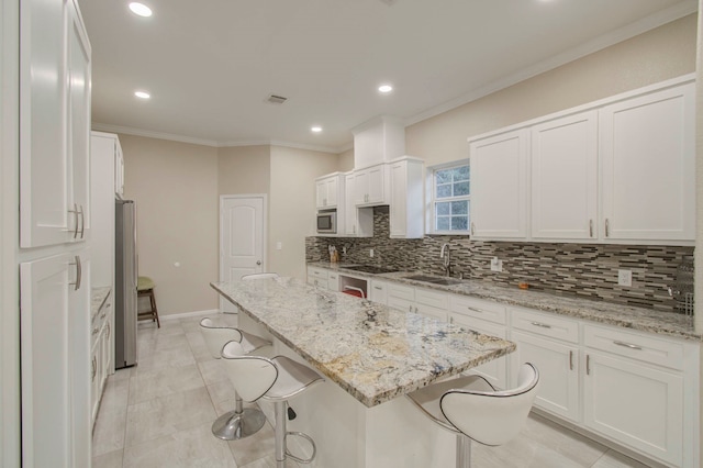 kitchen with white cabinetry, a center island, sink, and a kitchen bar