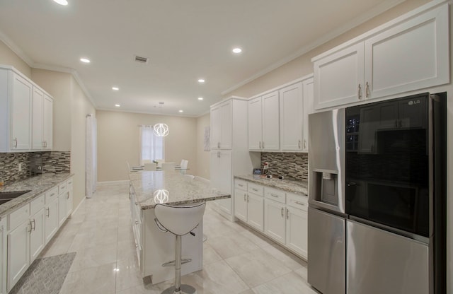 kitchen with stainless steel fridge, white cabinets, light stone counters, and tasteful backsplash