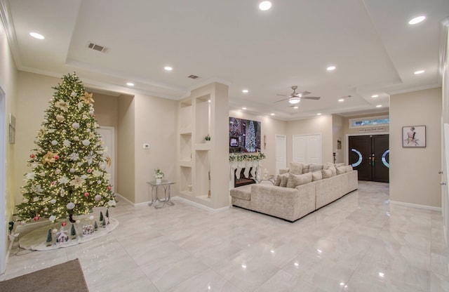 living room with ornamental molding, built in shelves, and ceiling fan