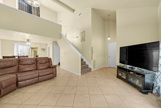 living room featuring beam ceiling, ceiling fan, a towering ceiling, and light tile patterned floors