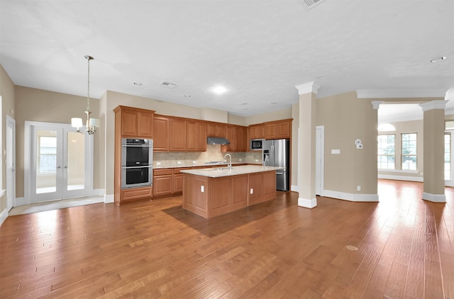 kitchen with stainless steel appliances, hardwood / wood-style flooring, plenty of natural light, and an island with sink