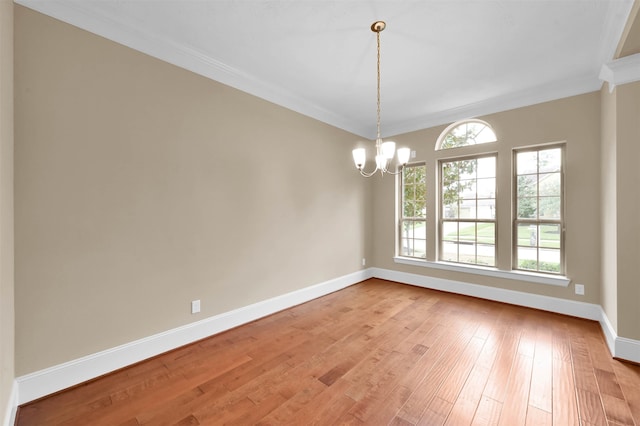 empty room featuring light hardwood / wood-style floors, a chandelier, and crown molding