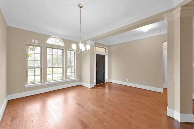 empty room with ornamental molding, a notable chandelier, hardwood / wood-style flooring, and decorative columns