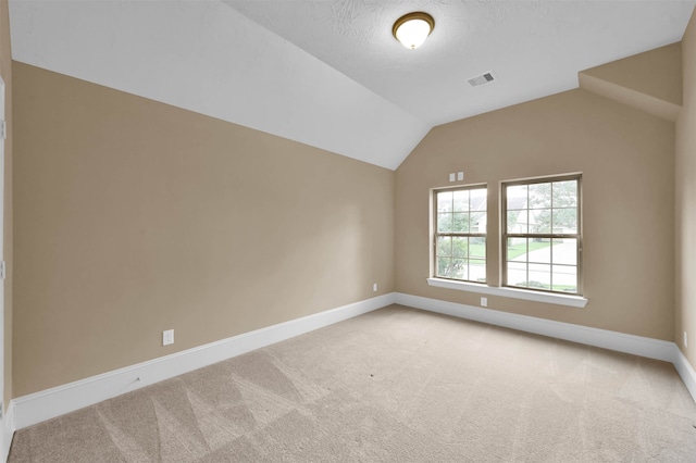 additional living space with carpet, vaulted ceiling, and a textured ceiling