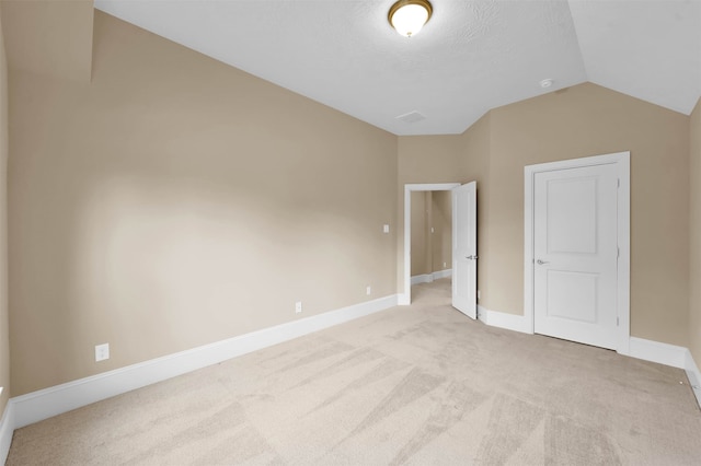 empty room with light carpet and vaulted ceiling