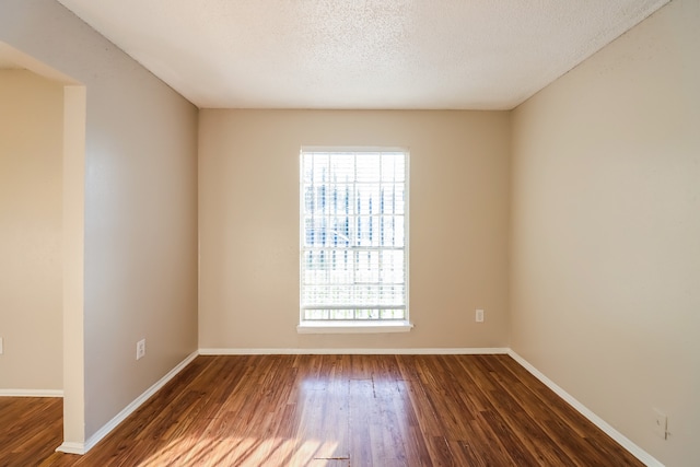 empty room featuring dark wood-type flooring and a textured ceiling