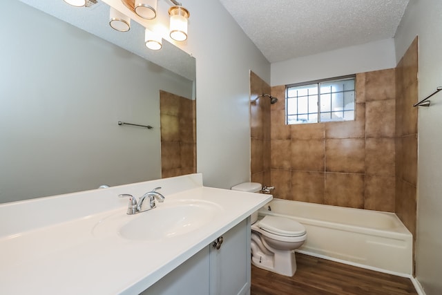 full bathroom featuring a textured ceiling, hardwood / wood-style floors, toilet, tiled shower / bath, and vanity