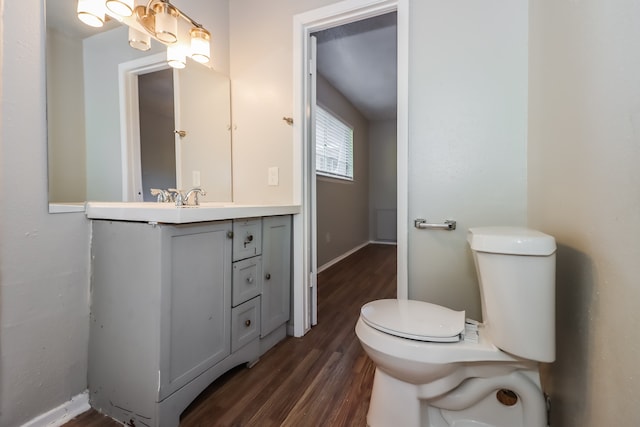 bathroom with toilet, vanity, and wood-type flooring