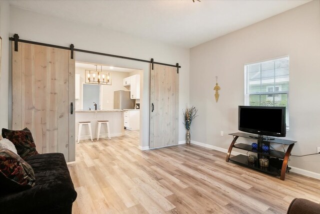 living room featuring light hardwood / wood-style floors, sink, and a barn door