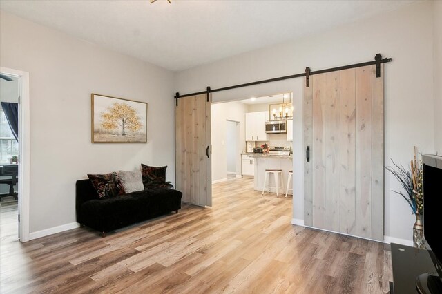 sitting room with a barn door and light hardwood / wood-style floors