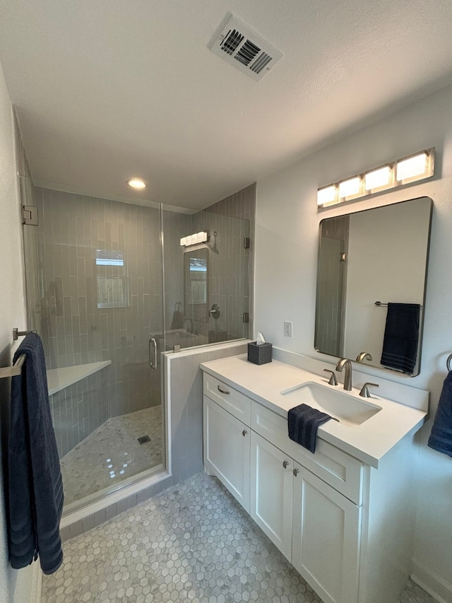 bathroom with vanity, a textured ceiling, and walk in shower