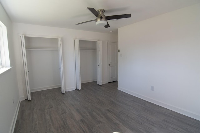 unfurnished bedroom with multiple closets, ceiling fan, and dark hardwood / wood-style flooring